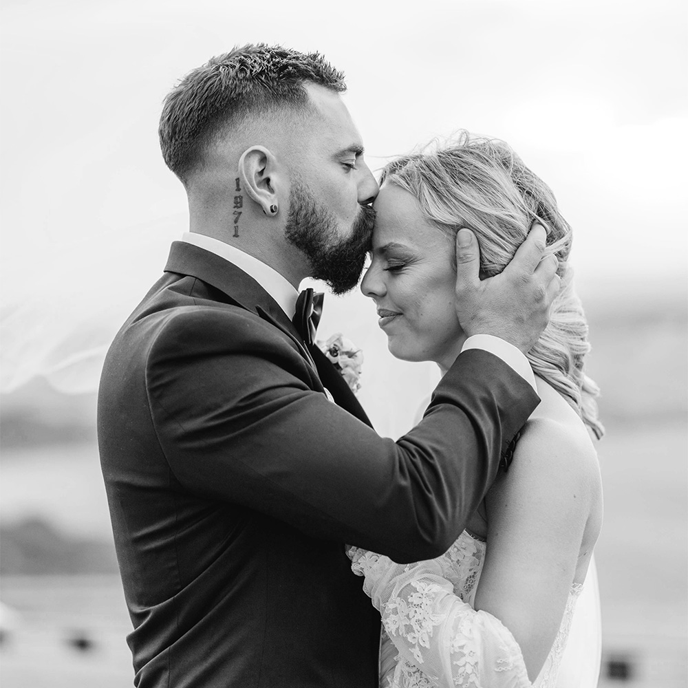 A groom kisses his bride on the forehead at Marnong Estate
